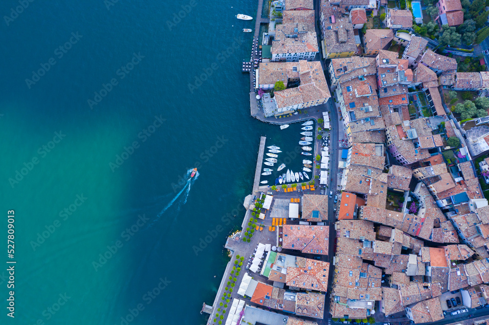 Gargnano at Lake Garda. aerial view. Small marina in Italian village. ferry and boats leaving the harbour. Top view of a cosy Italian fishing village. Port on the edge of Lago di Garda in Brescia