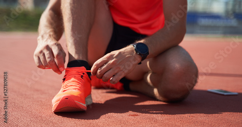 Sport man athlete tying laces for jogging on treadmillat the stadium.