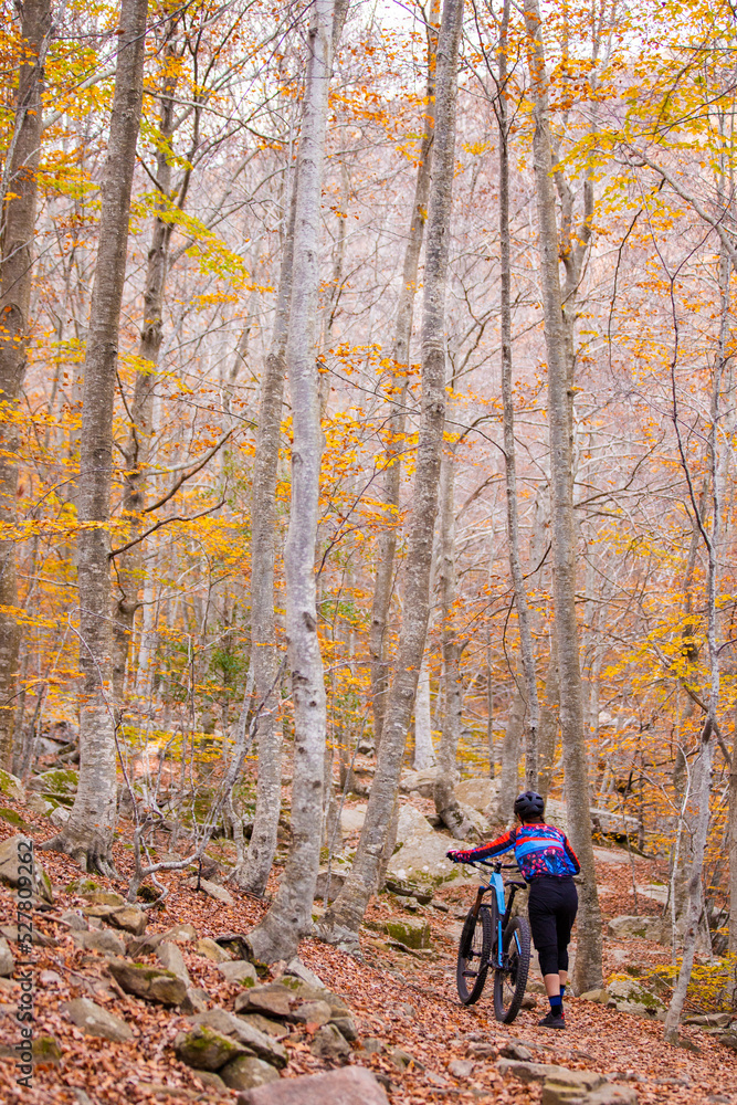 Woman in helmet walking with mountain bike in forest Woman in helmet walking with mountain bike in forest