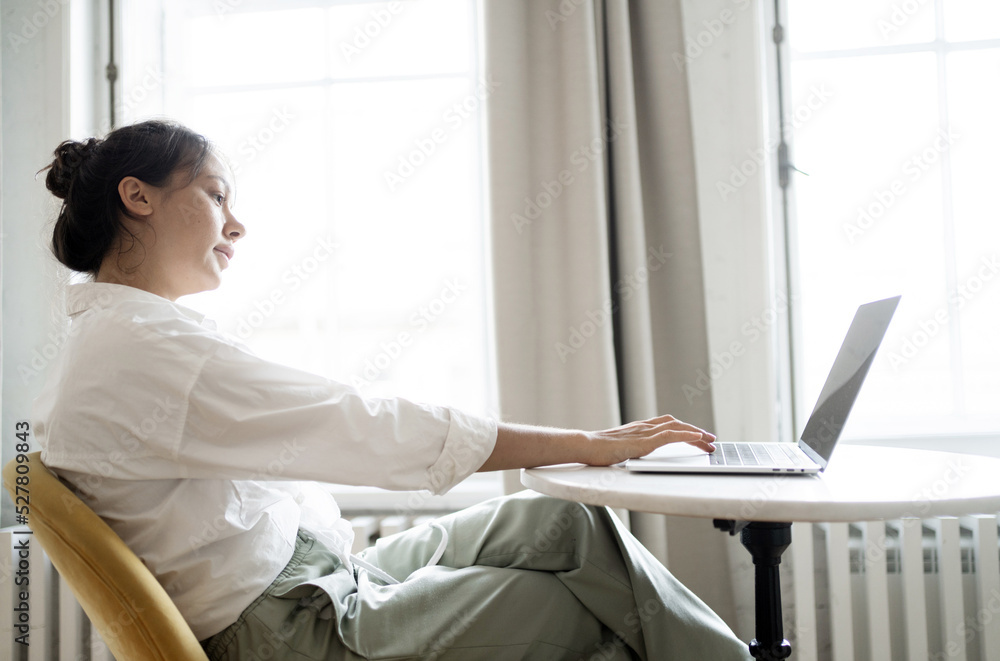 A female blogger works in an online office doing a design project on a website. The programmer uses a laptop and communicates with the client A female blogger works in an online office doing a design project on a website. The programmer uses a laptop and communicates with the client