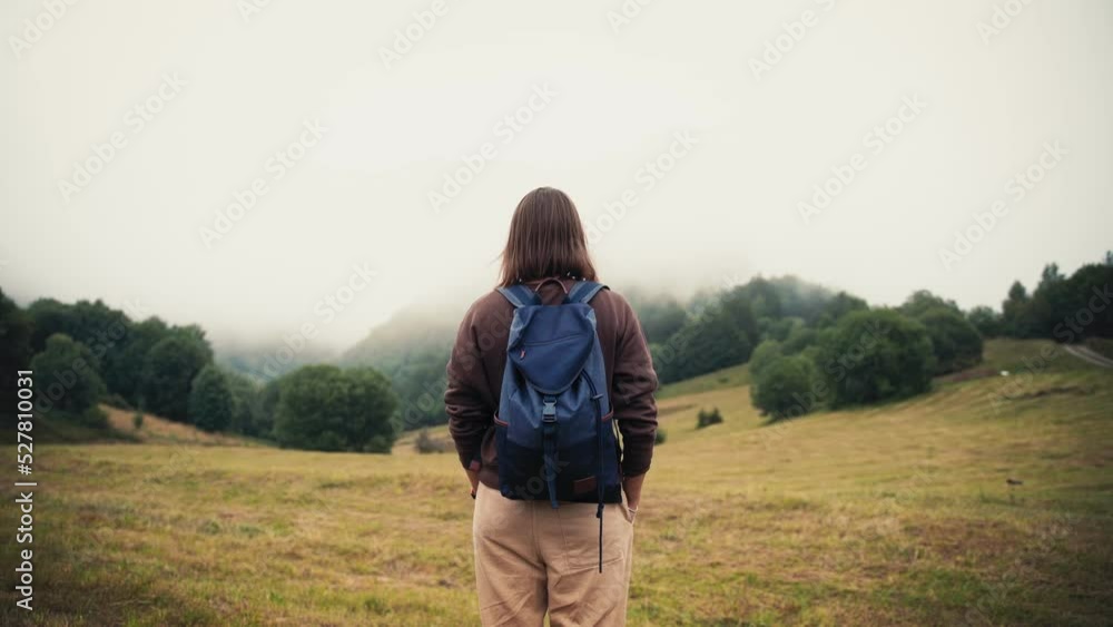 A back shot of a person with a backpack enjoying the beautiful view of the mountains covered with fog in autumn. A back shot of a person with a backpack enjoying the beautiful view of the mountains covered with fog in autumn.