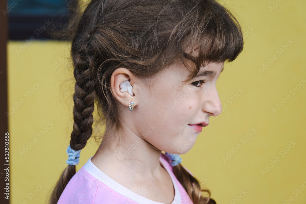 Girl with a warming therapeutic cotton swab in the ear with a sad and