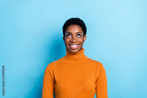 Photo of beautiful cheerful female look up empty space see product promotion isolated on blue color background