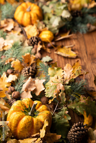 Autumn composition on a rustic wooden background. Decorative pumpkins  various leaves   pine cones  nuts. Orange  yellow  red  and brown aesthetics.  