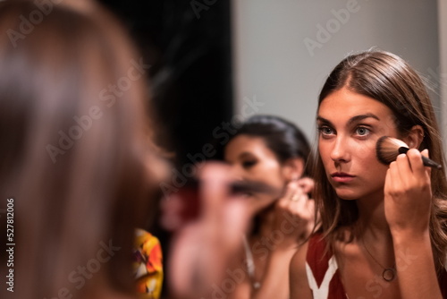 Cheerful young female friends refresh makeup in bathroom