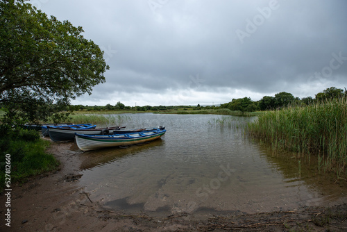 paysage d'Irlande, vue sur un lac. Des petites barques sont amarrées et flottent paisiblement