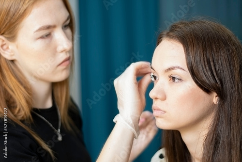 People. Beauty saloon. A beautiful Caucasian girl undergoing eyebrow correction by a make-up artist.