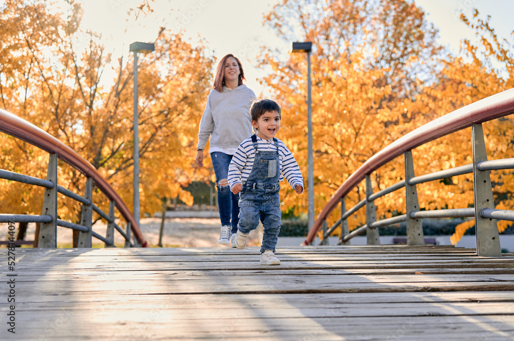 Happy child and mother on bridge in park Happy child and mother on bridge in park