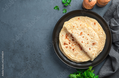 Fresh Indian chapati tortillas with fresh parsley on a graphite background. Top view, copy space