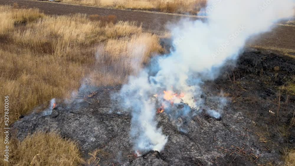 Aerial view of waste pile burning with red fire on grassland field during dry season. Natural disaster and climate pollution concept
