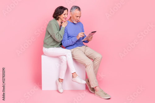 Full body photo of two idyllic partners sit podium use wireless tablet isolated on pink color background