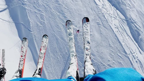 Legs and two people with pairs of skis dangling over tracks