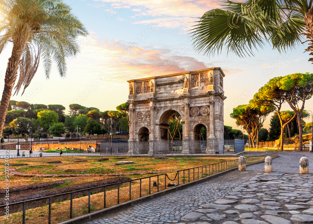 The Arch of Constantine behind the palms, famous place of visit in Rome, Italy