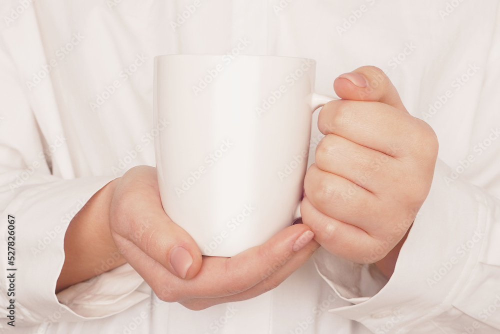 Woman hands holding mock up white cup, mug close-up on beige background. Blank template, logo, text design, promotional, text message. Woman hands holding mock up white cup, mug close-up on beige background. Blank template, logo, text design, promotional, text message.