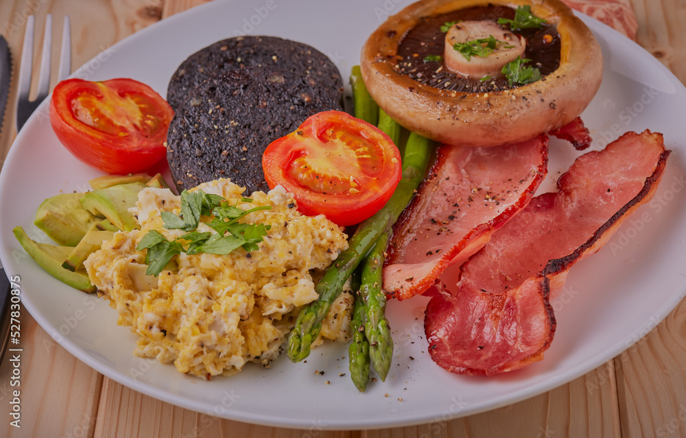 Healthy cooked breakfast on white plate with wooden background.