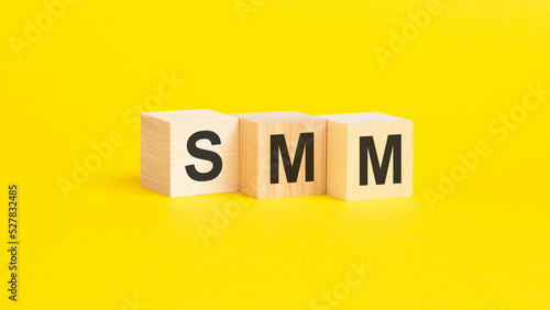 wooden blocks with text SMM on yellow background. business concept