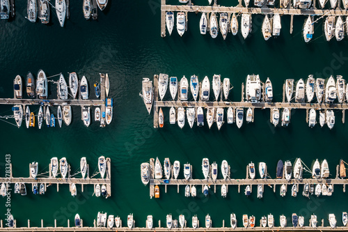 Aerial top down view of many luxurious yachts moored in marina