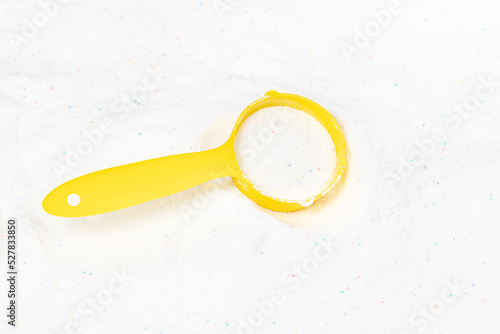 Laundry detergent for washing machines and a plastic scoop for dosing. Washing powder with measuring spoon. White wash powder with with colored granules © Илья Подопригоров