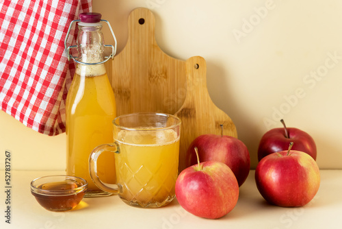 Apple Cider Vinegar in Glass Mug and Bottle with Honey and Cinnamon Red Apples Yellow Background Horizontal