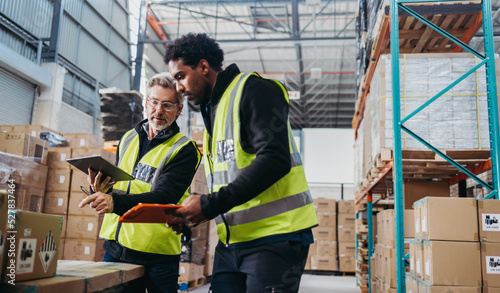 Mature warehouse manager training a new employee in order fulfilment