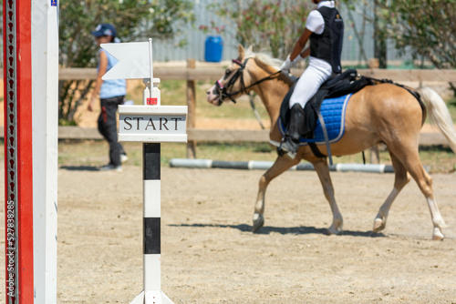 Close up on Start Signage on Blurred girl that rides a Pony during Pony Game Competition