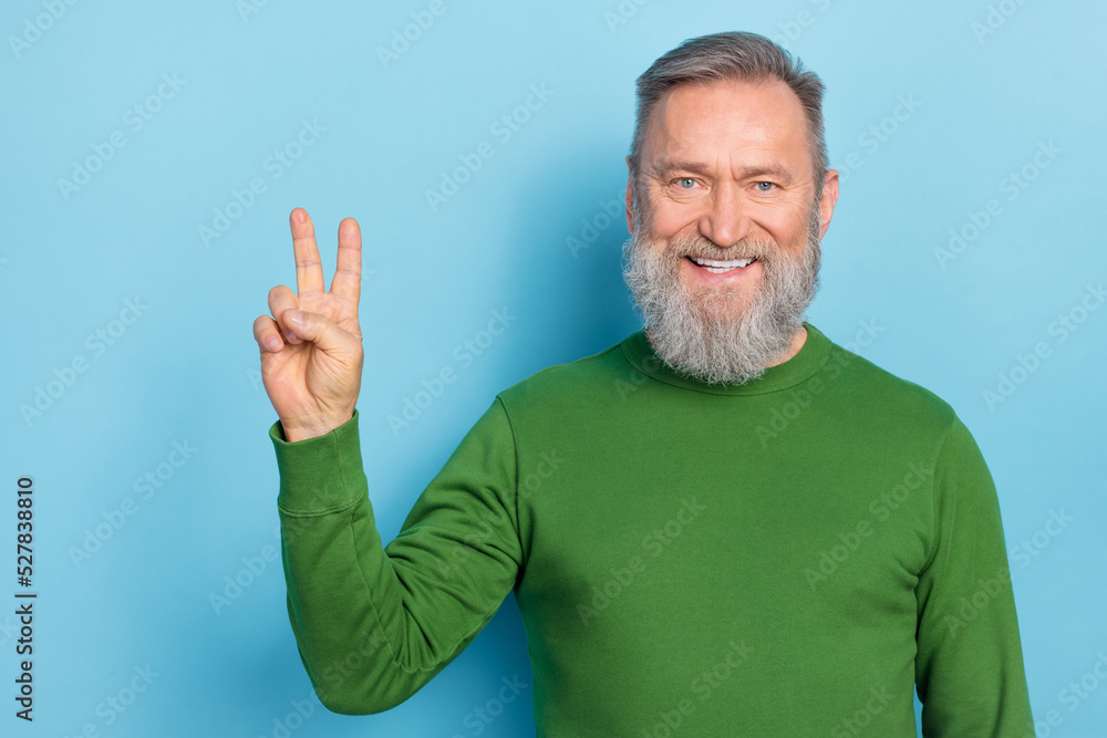 Photo of smiling grandpa meet friend saying hello making v sign isolated on blue color background Photo of smiling grandpa meet friend saying hello making v sign isolated on blue color background