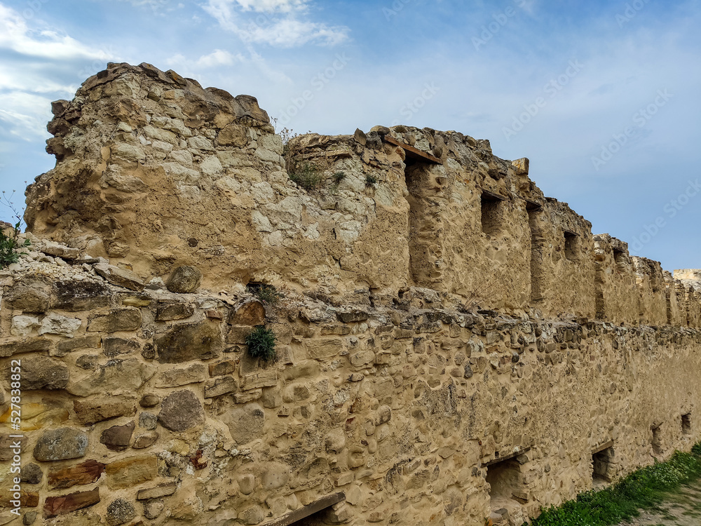 Wall of ancient Rupa fortress in Romania against blue sky with clouds. Fortress was built on ruins of former Dacian defensive structure. Copy space. Selective focus.