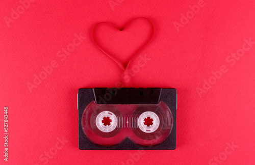 Audio cassette with a film heart on a pink background. Valentine's Day