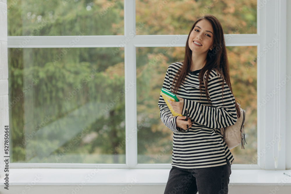 Portrait of a smiling student girl with notebooks and a backpack. The concept of school and college education Portrait of a smiling student girl with notebooks and a backpack. The concept of school and college education