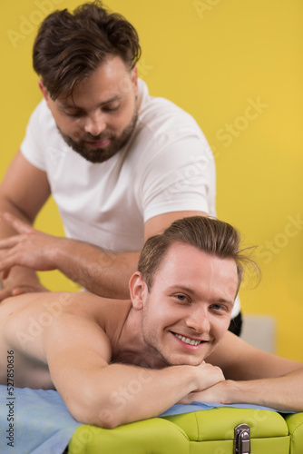 Medical clinic the professional therapist working with his client while the man are laying down on the massage table masseur massage week the hands and muscles and back of his client