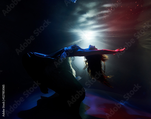 a girl in a beautiful dress dances in the light of lanterns under water ballet