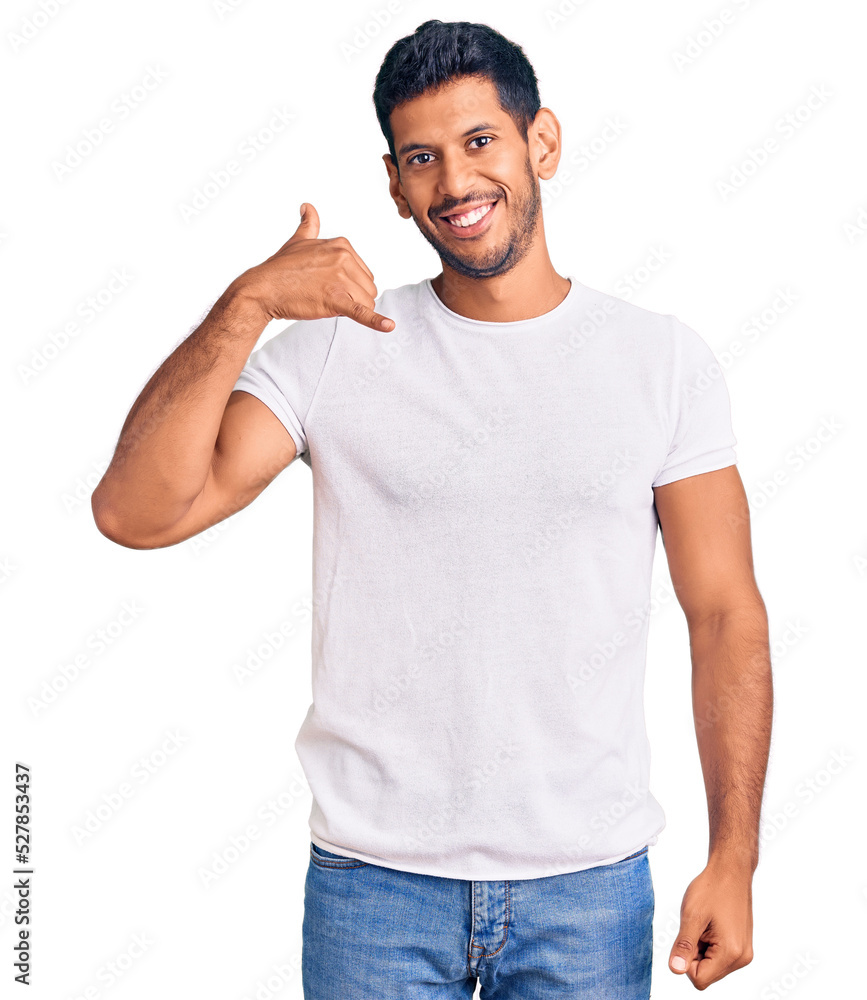 Young latin man wearing casual clothes smiling doing phone gesture with hand and fingers like talking on the telephone. communicating concepts. Young latin man wearing casual clothes smiling doing phone gesture with hand and fingers like talking on the telephone. communicating concepts.