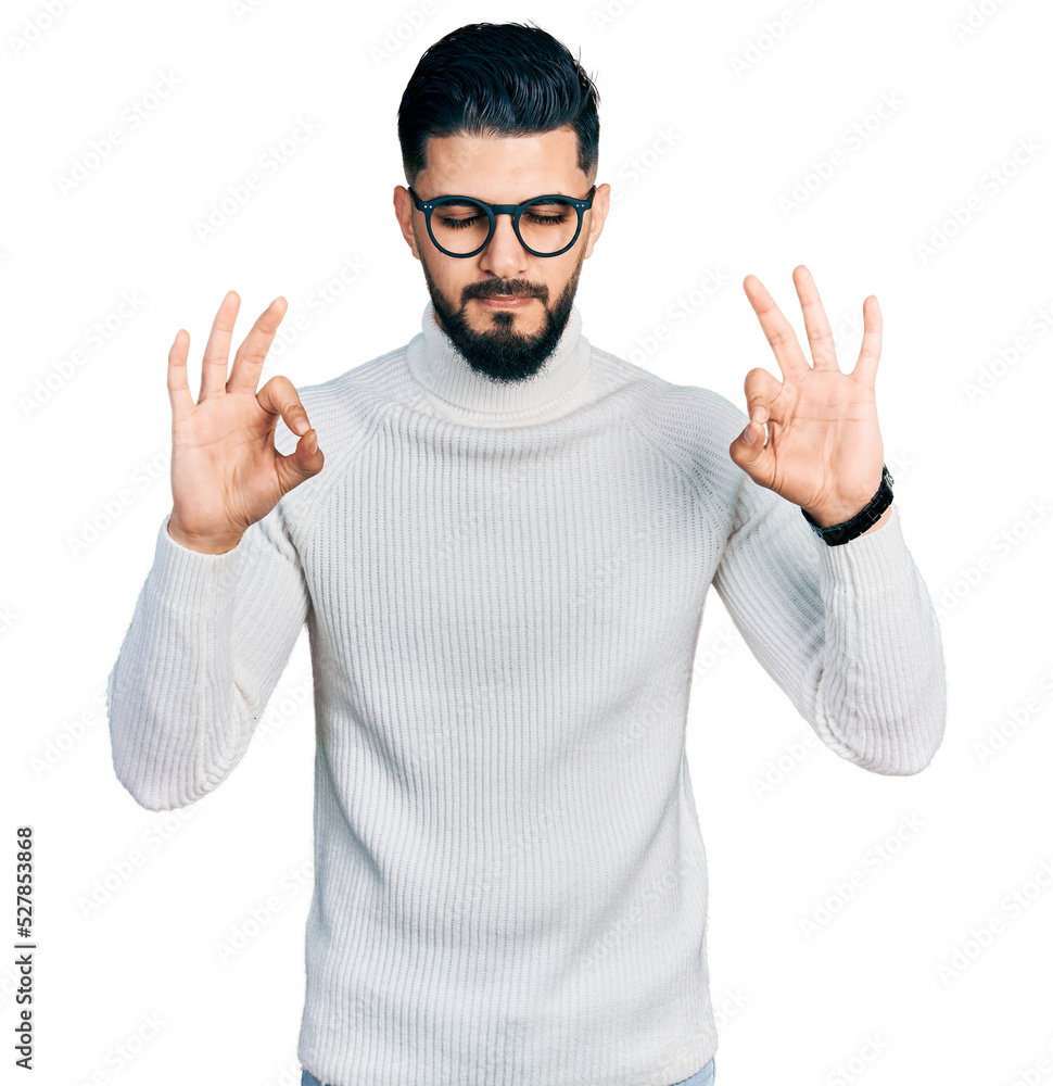 Young arab man with beard wearing elegant turtleneck sweater and glasses relaxed and smiling with eyes closed doing meditation gesture with fingers. yoga concept. Young arab man with beard wearing elegant turtleneck sweater and glasses relaxed and smiling with eyes closed doing meditation gesture with fingers. yoga concept.