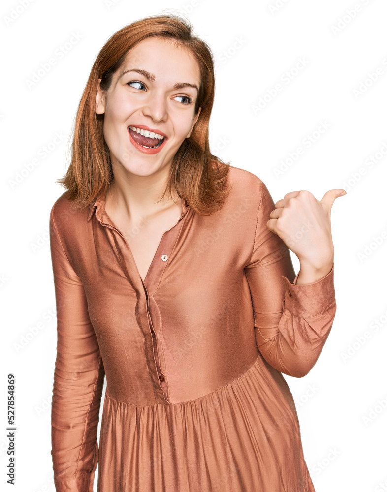 Young caucasian woman wearing sexy party dress smiling with happy face looking and pointing to the side with thumb up. Young caucasian woman wearing sexy party dress smiling with happy face looking and pointing to the side with thumb up.