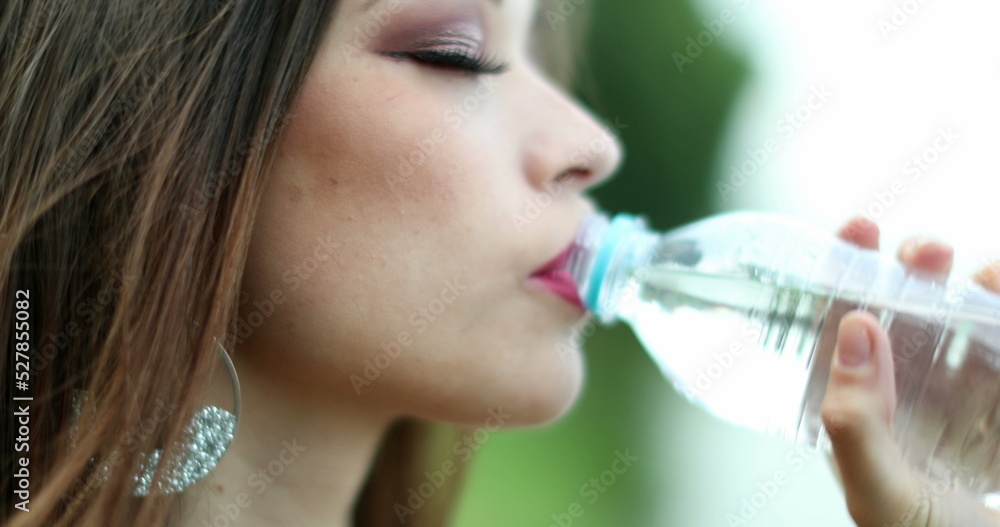 Young woman drinking water in bottle outdoors Young woman drinking water in bottle outdoors