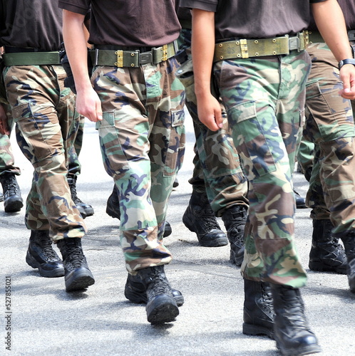 Soldiers in military uniform marching outside.