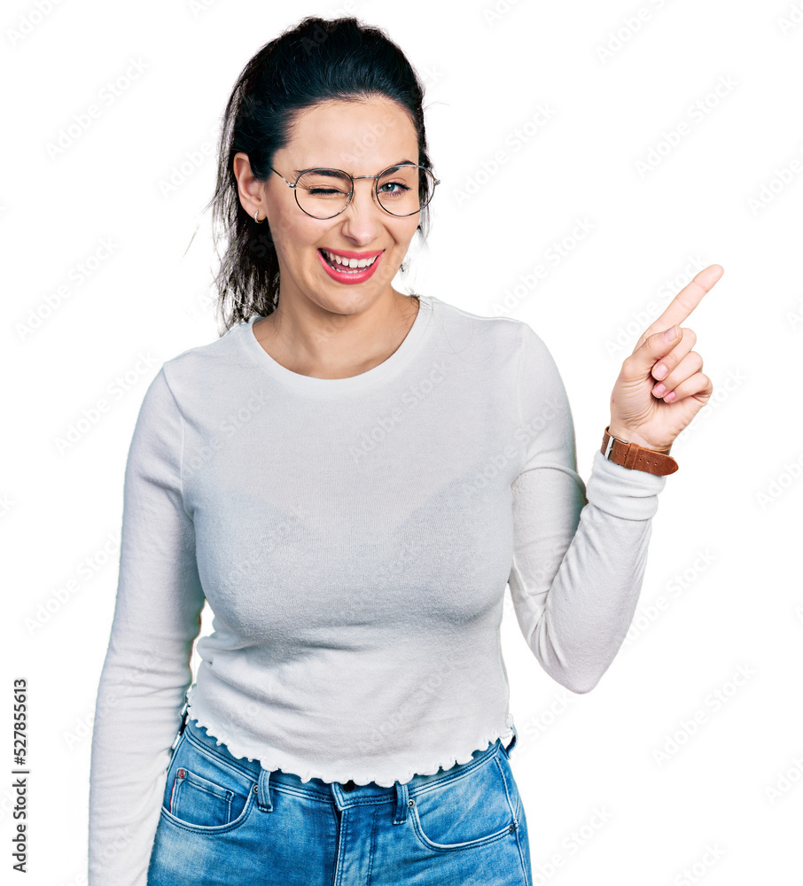 Young hispanic woman pointing with fingers to the side winking looking at the camera with sexy expression, cheerful and happy face. Young hispanic woman pointing with fingers to the side winking looking at the camera with sexy expression, cheerful and happy face.