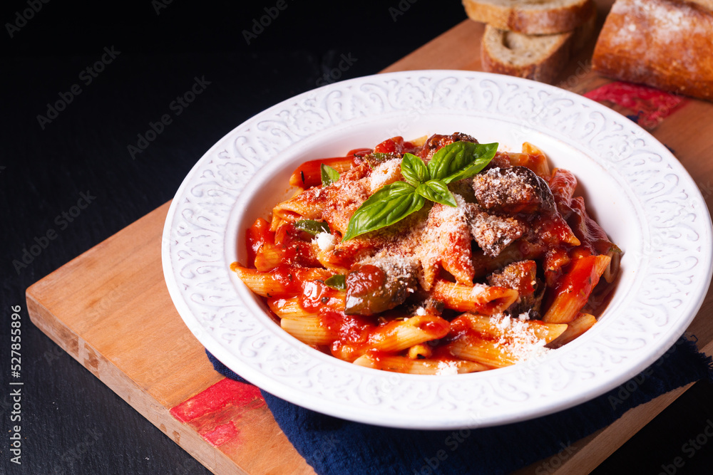 Food concept homemade organic Sicilian pasta alla norma Penne with eggplant tomato sauces on wooden board on black background with copy space Food concept homemade organic Sicilian pasta alla norma Penne with eggplant tomato sauces on wooden board on black background with copy space