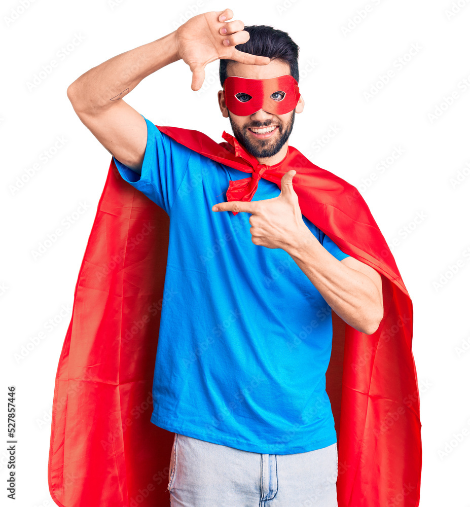 Young handsome man with beard wearing super hero costume smiling making frame with hands and fingers with happy face. creativity and photography concept. Young handsome man with beard wearing super hero costume smiling making frame with hands and fingers with happy face. creativity and photography concept.