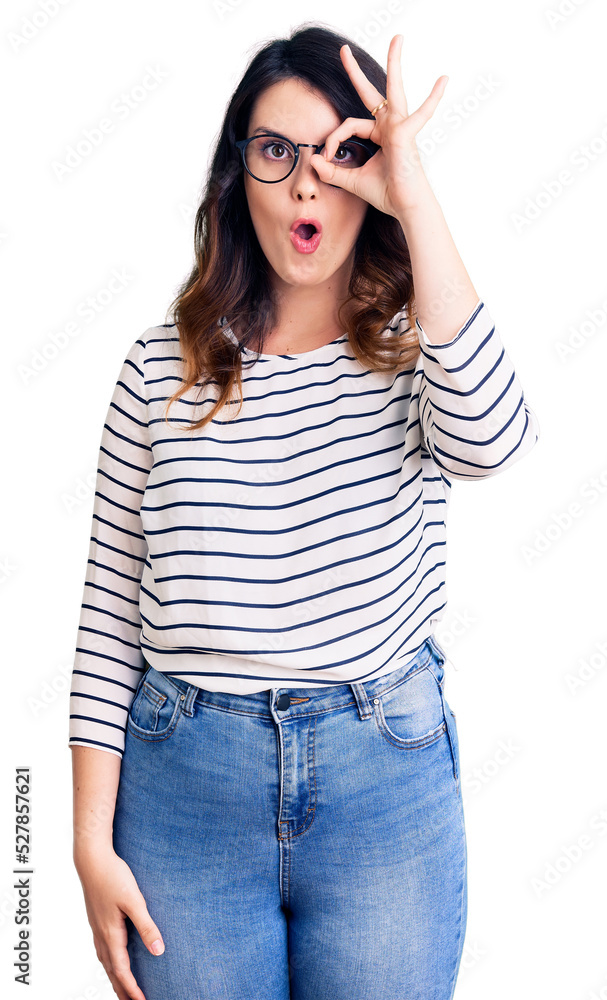 Beautiful young brunette woman wearing casual clothes and glasses doing ok gesture shocked with surprised face, eye looking through fingers. unbelieving expression. Beautiful young brunette woman wearing casual clothes and glasses doing ok gesture shocked with surprised face, eye looking through fingers. unbelieving expression.