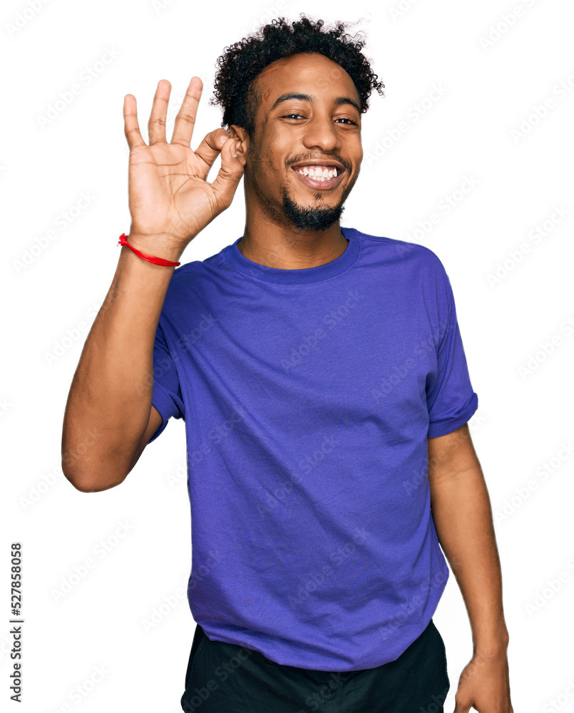 Young african american man with beard wearing casual purple t shirt smiling positive doing ok sign with hand and fingers. successful expression. Young african american man with beard wearing casual purple t shirt smiling positive doing ok sign with hand and fingers. successful expression.