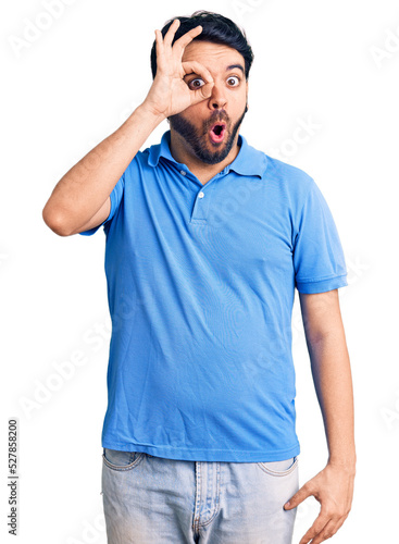 Young hispanic man wearing casual clothes doing ok gesture shocked with surprised face, eye looking through fingers. unbelieving expression. © Krakenimages.com