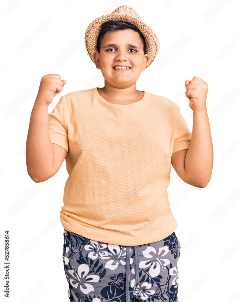 Little boy kid wearing summer hat and hawaiian swimsuit celebrating surprised and amazed for success with arms raised and open eyes. winner concept. Little boy kid wearing summer hat and hawaiian swimsuit celebrating surprised and amazed for success with arms raised and open eyes. winner concept.