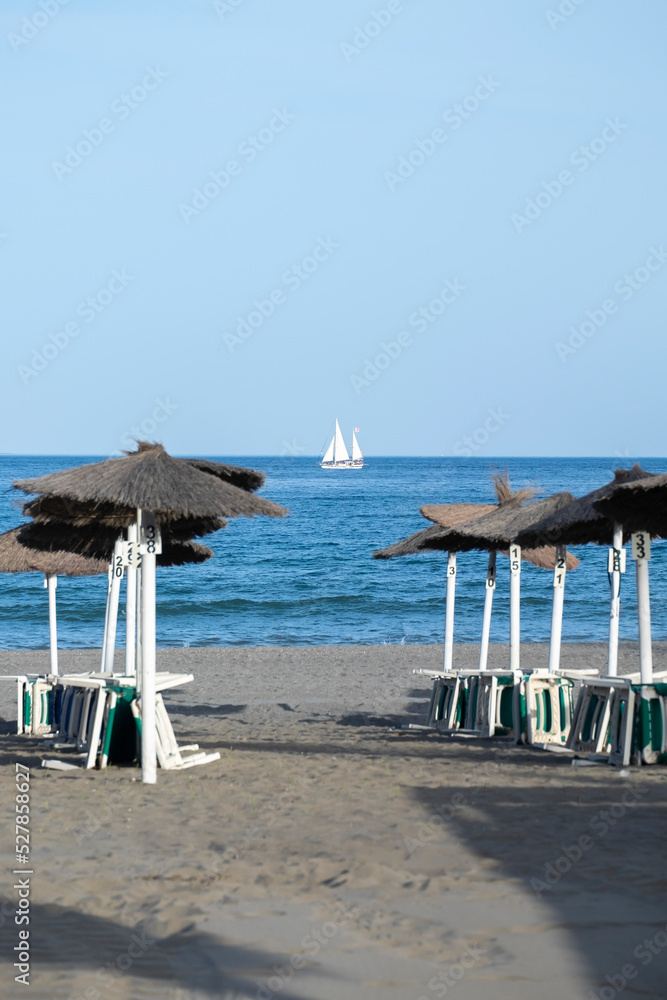 Straw beach umbrellas and comfortable sun loungers on Maditerranean's shore. Straw beach umbrellas and comfortable sun loungers on Maditerranean's shore.