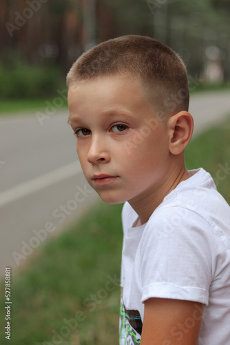 A dark-skinned boy with brown eyes and a white T-shirt looks into the camera lens  close-up