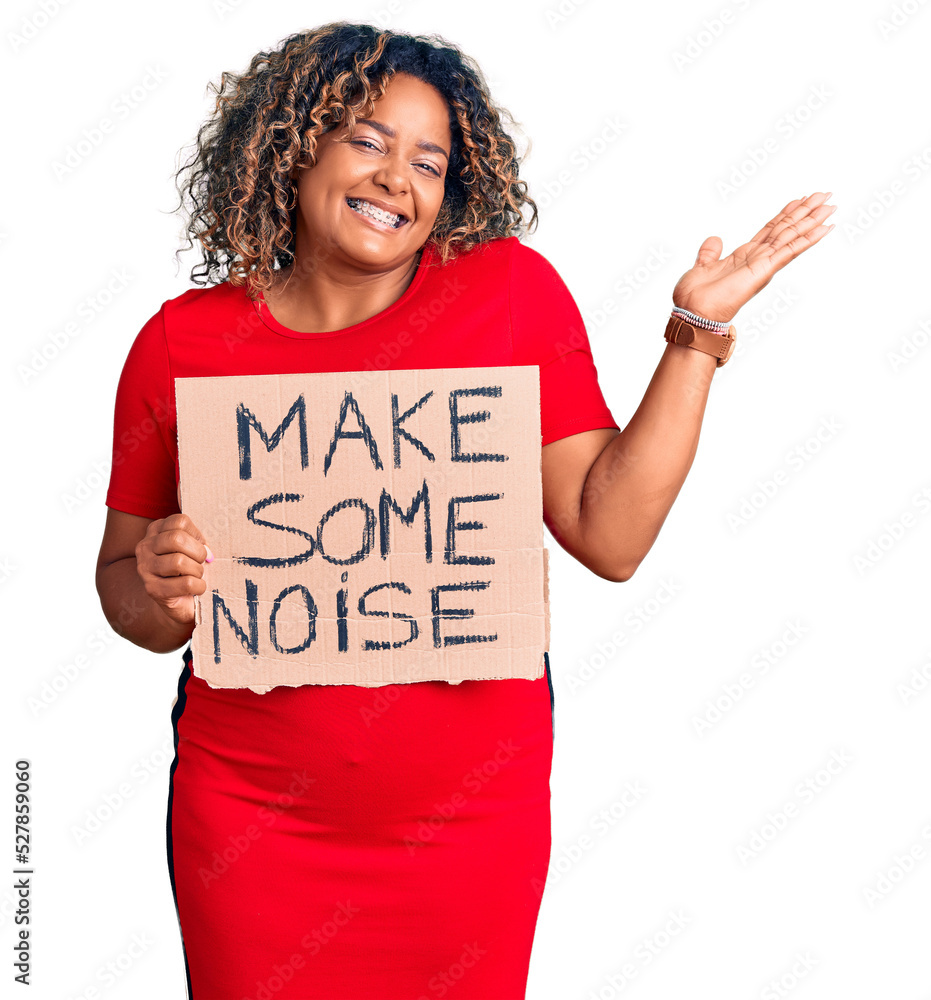 Young african american plus size woman holding make some noise banner celebrating victory with happy smile and winner expression with raised hands Young african american plus size woman holding make some noise banner celebrating victory with happy smile and winner expression with raised hands