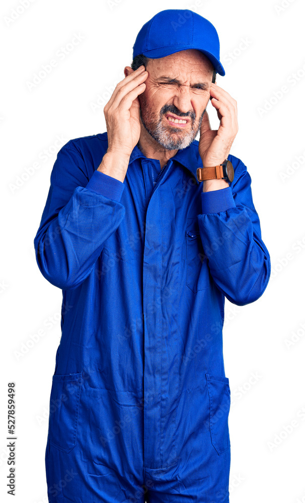 Middle age handsome man wearing mechanic uniform covering ears with fingers with annoyed expression for the noise of loud music. deaf concept. Middle age handsome man wearing mechanic uniform covering ears with fingers with annoyed expression for the noise of loud music. deaf concept.