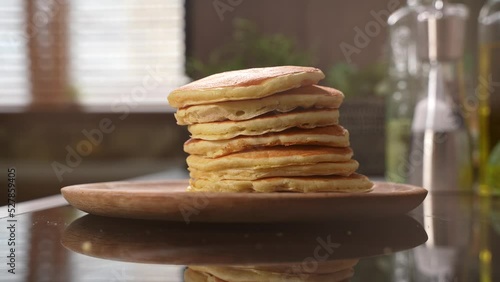 Stack of delicious pancakes drops in wooden plate. Stack of american style fluffy buttermilk pancakes for sweet breakfast. High quality 4k footage