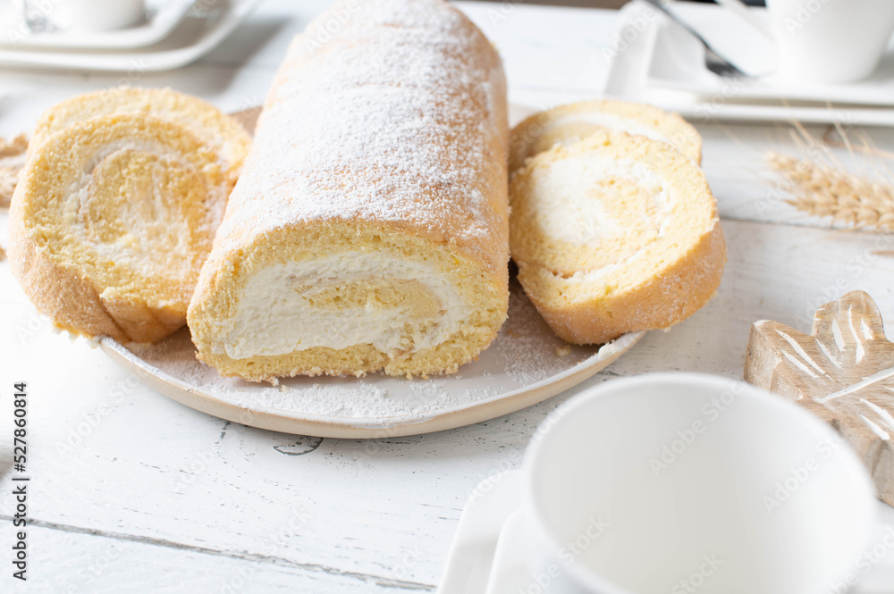 Swiss roll with whipped cream filling on a white coffee table Swiss roll with whipped cream filling on a white coffee table