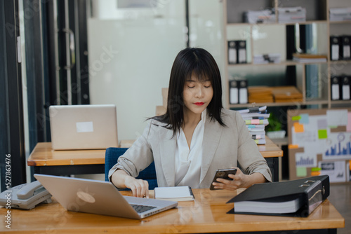Asian businesswoman working with calculator and laptop computer at office workplace. business planning, investment and marketing on table in office. 